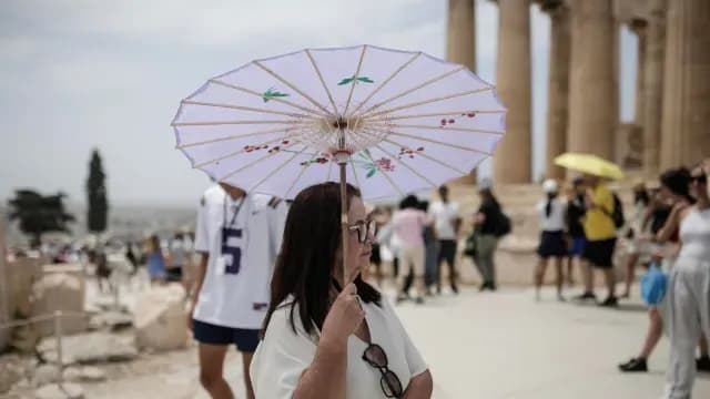 Turista se cubre del Sol mientra pasea por la Acrópolis