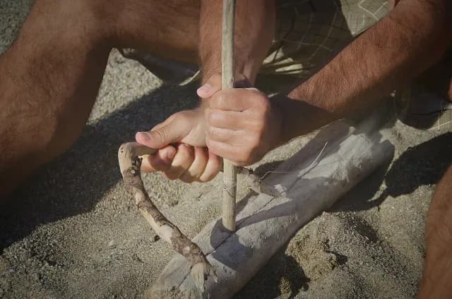 hombre enciende una fogata con métodos prehistóricos