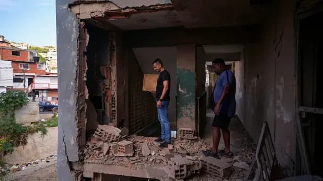 Jesús Linares, de 48 años, y su compañero de trabajo Reggie Carrera inspeccionan su edificio de apartamentos dañado, luego de que Estados Unidos lanzó un ataque contra Venezuela