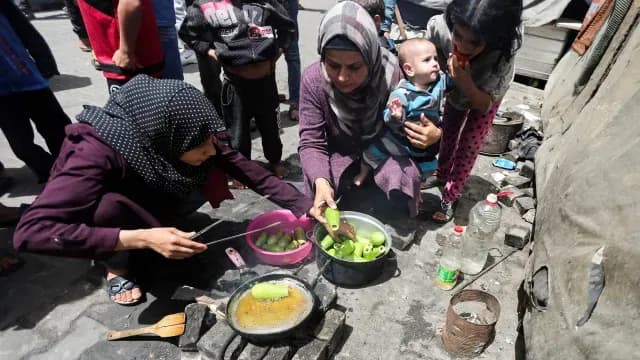 Palestinos desplazados tras ataques israelíes cocinan