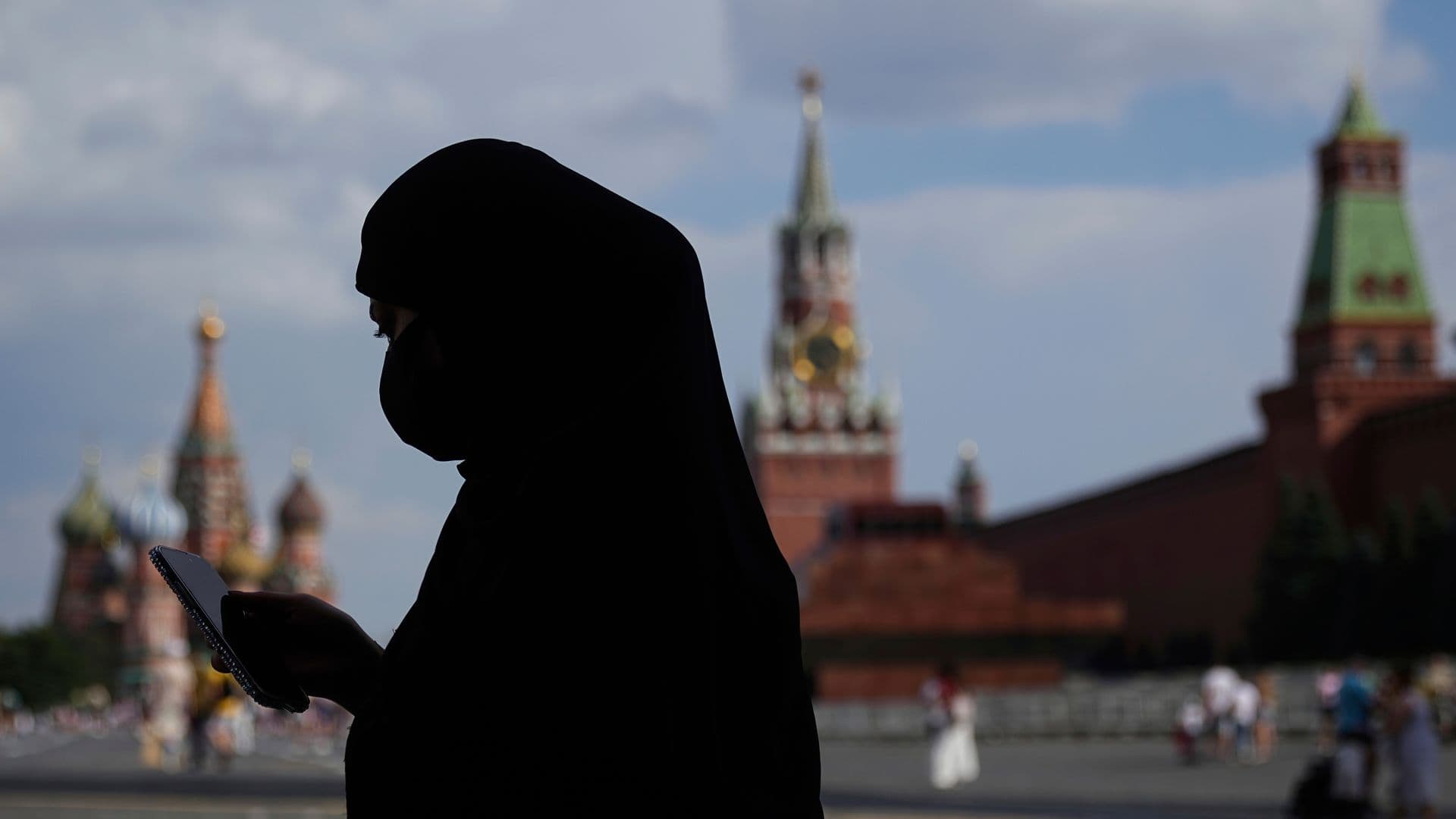 Una mujer, vestida con niqab, consulta su celular mientras camina por la Plaza Roja, en Moscú, Rusia. Foto: AP