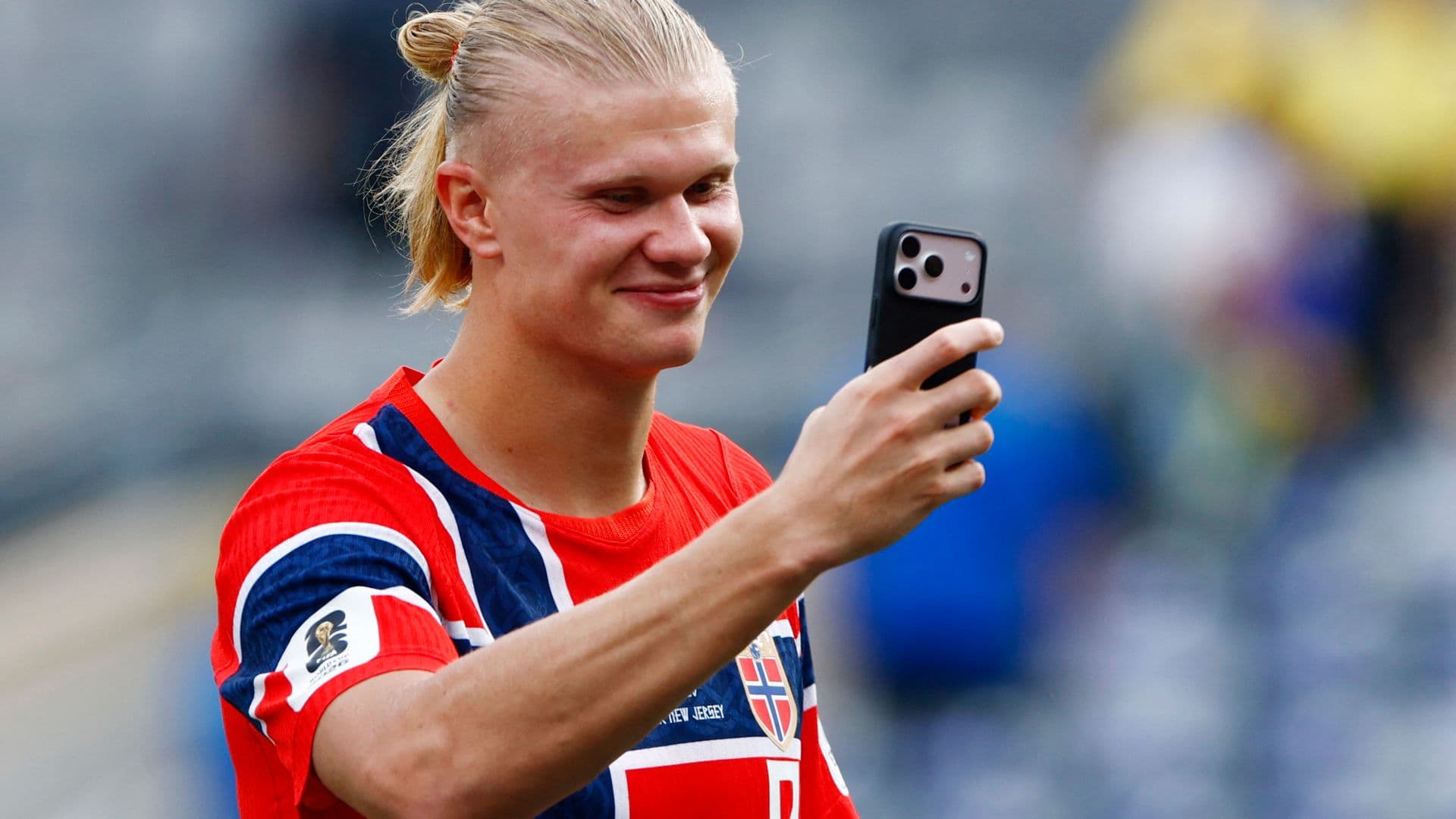 Erling Haaland, de Noruega , sostiene su teléfono en el campo. Foto: Reuters