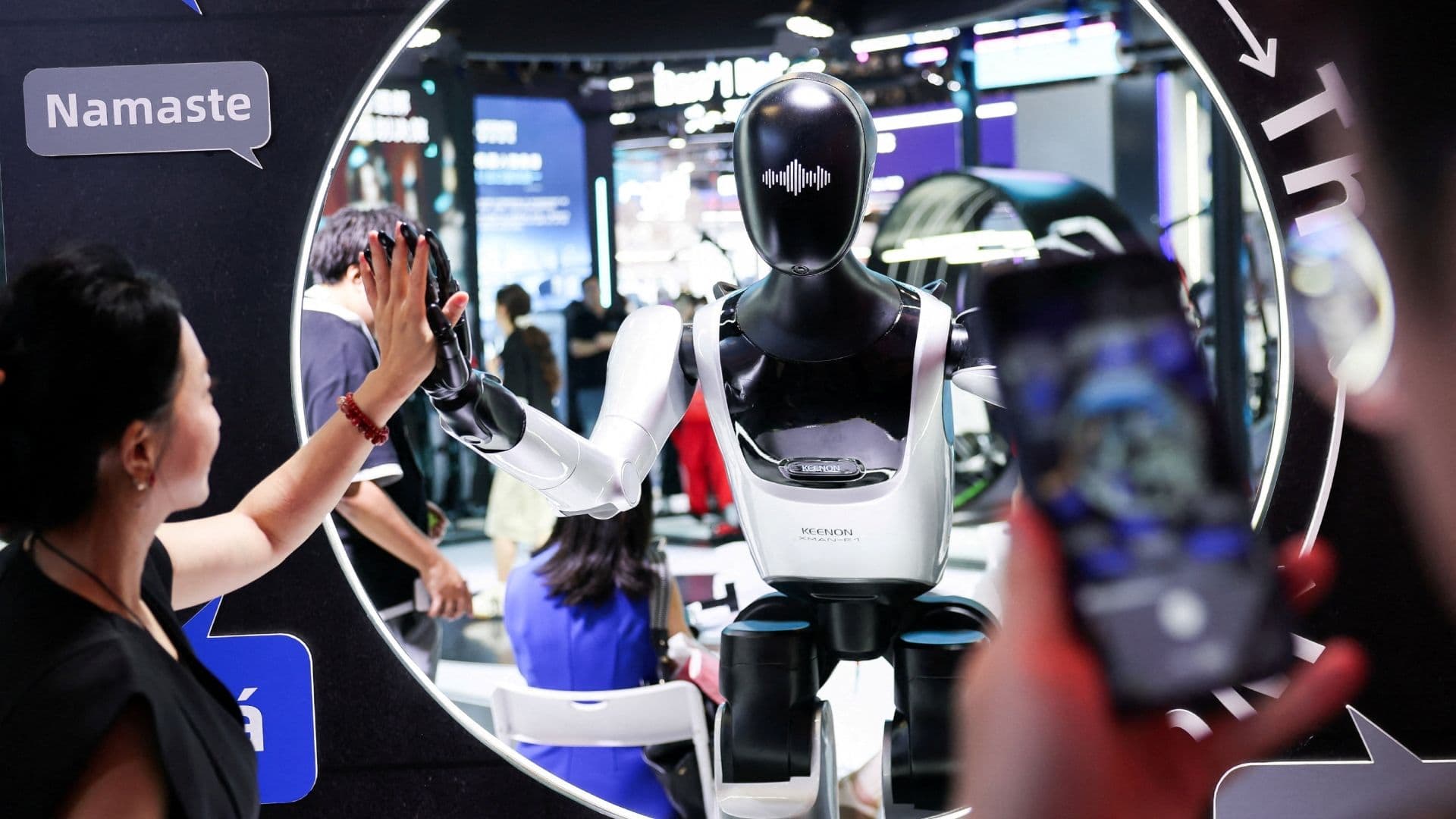 Un visitante choca la mano con un robot humanoide en la Conferencia Mundial de Inteligencia Artificial (WAIC) en Shanghái