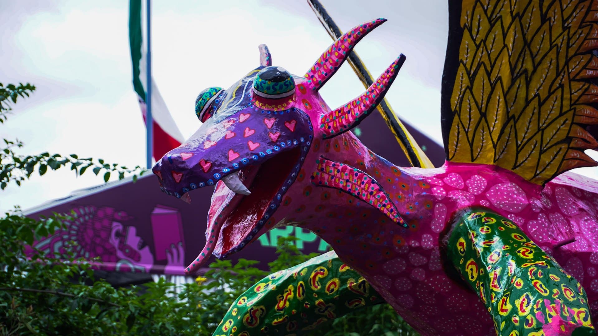 Detalle de la cabeza de un alebrije en tonos rosa y morado, con corazones pintados en el hocico. Foto: N+