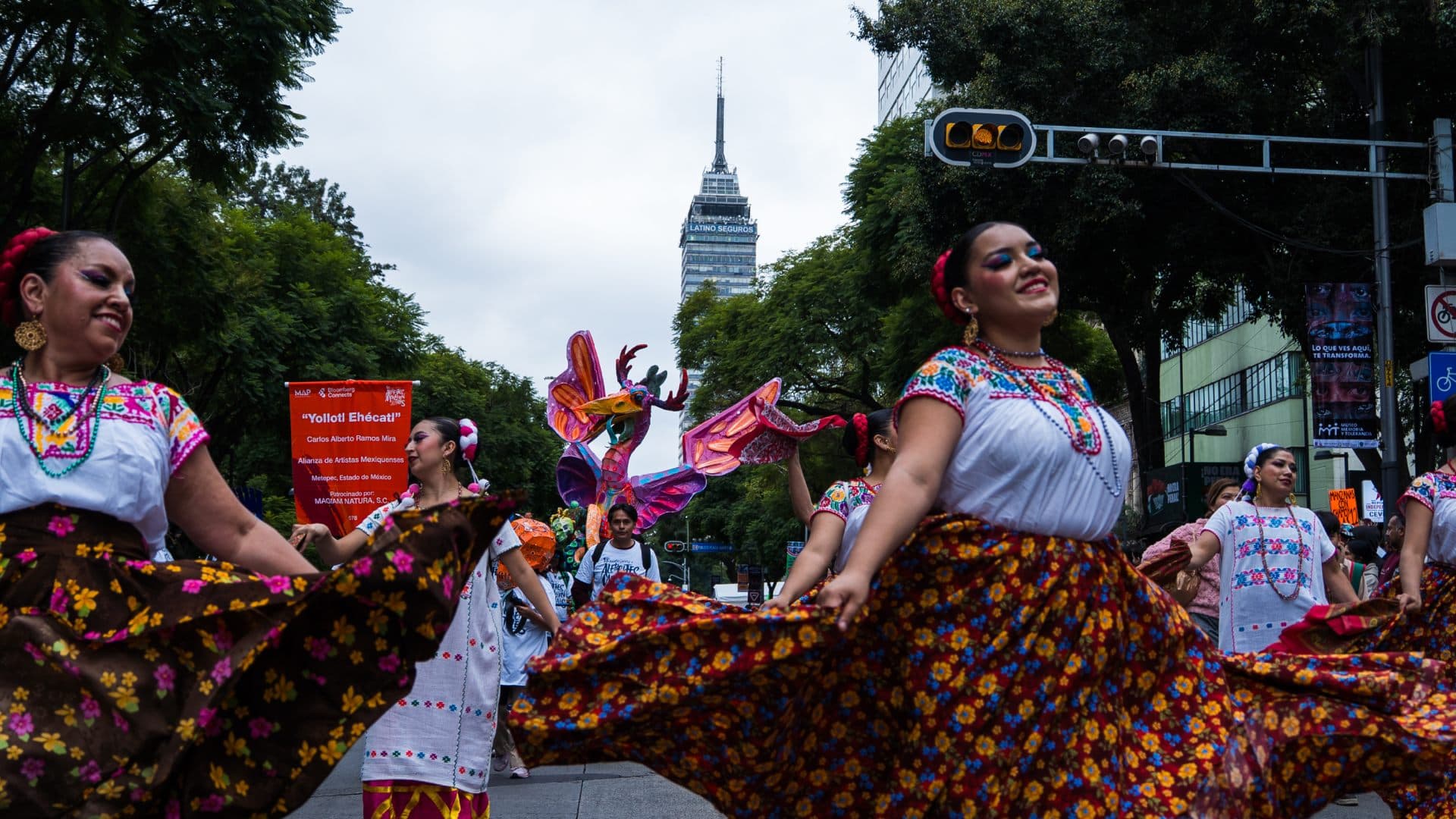 Bailarinas con vestimenta tradicional acompañan al alebrije "Yollotl Ehécatl", de Carlos Alberto Ramos Mira, con la Torre Latinoamericana al fondo. Foto: N+