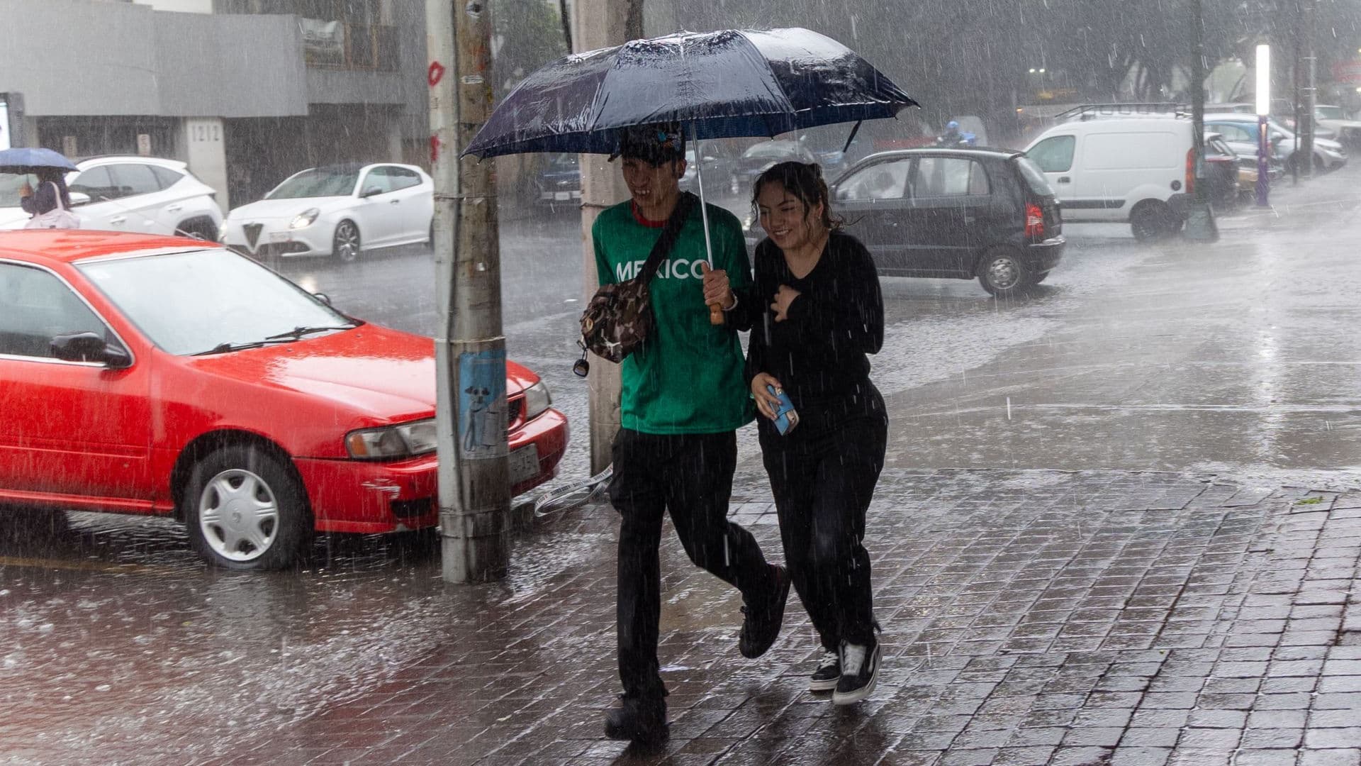 Dos jóvenes intentan protegerse de la lluvia en la CDMX
