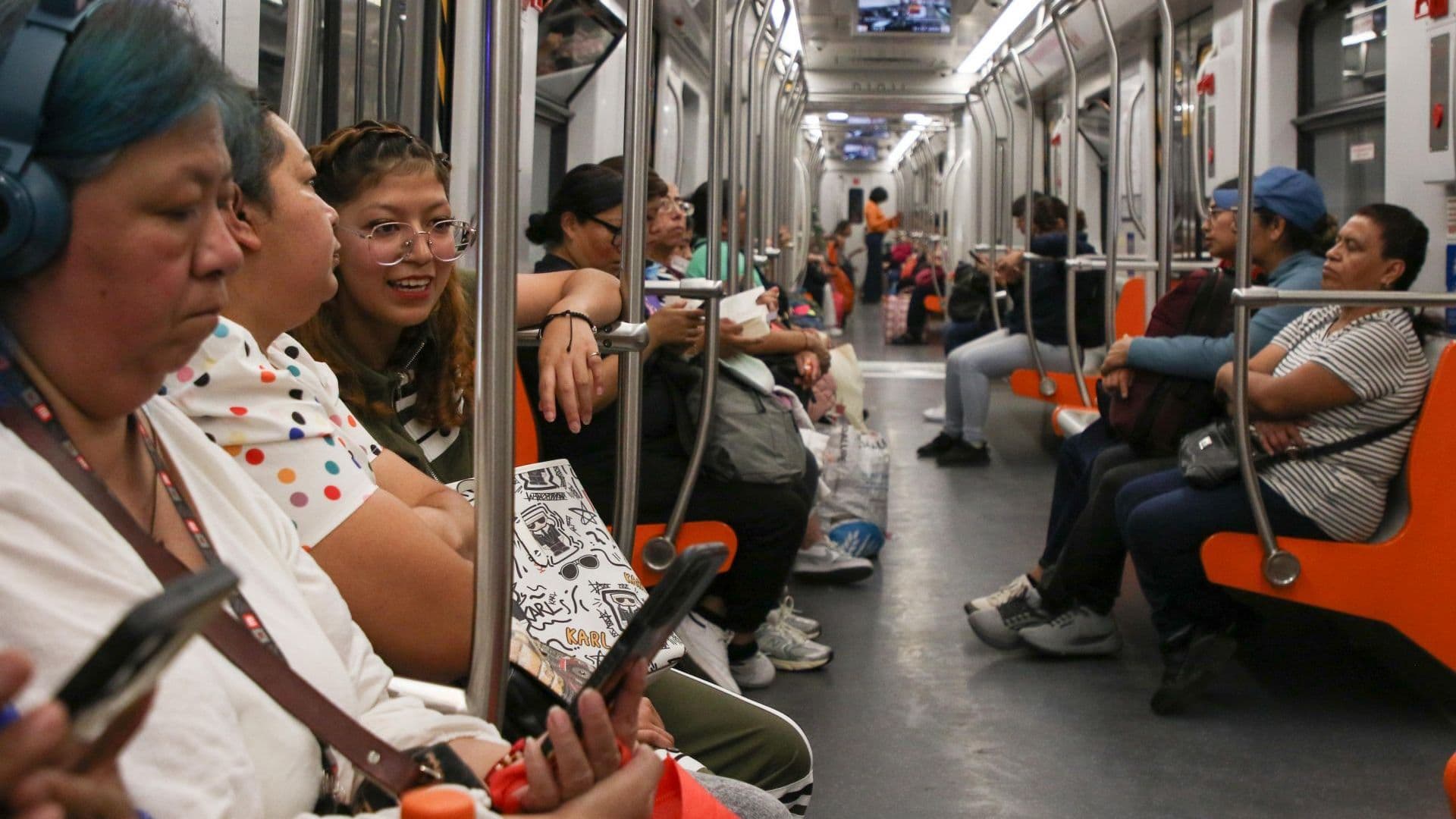 Personas revisan su teléfono celular dentro de vagón del Metro CDMX.