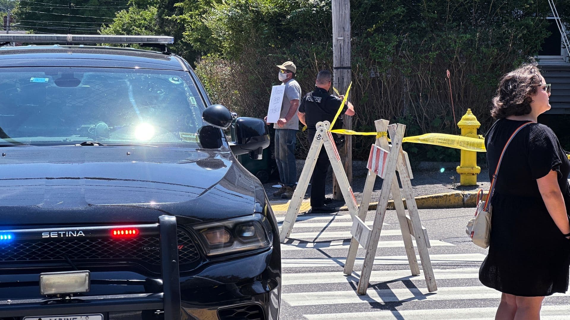 Personas observan el operativo mientras autoridades mantienen cerrada una carretera tras un tiroteo relacionado con agentes del ICE en Biddeford, Maine.