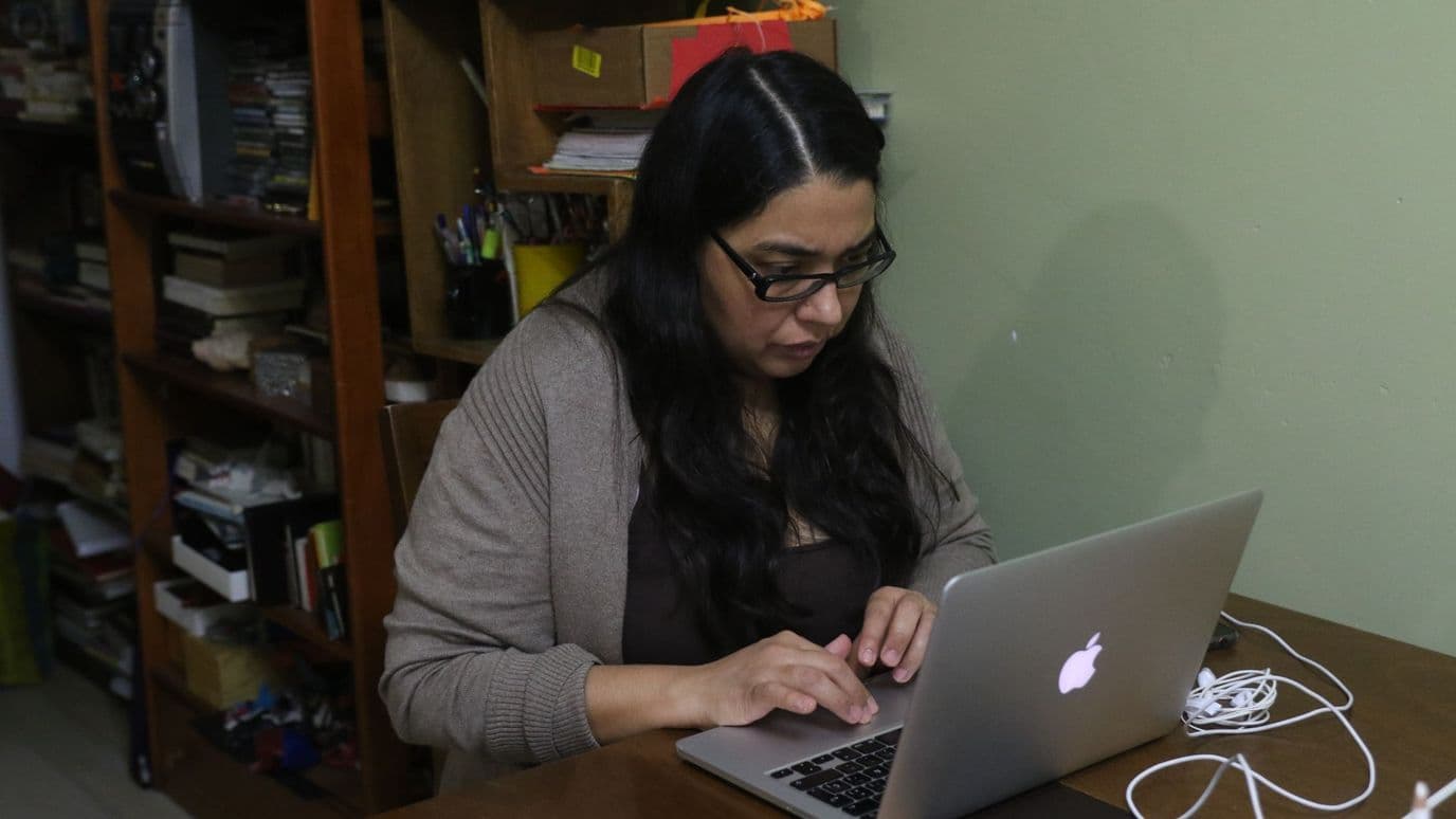 Un mujer realiza home office, mientras que su hijo juega