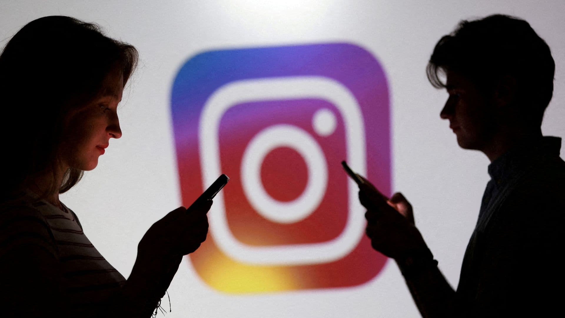 Adolescentes posan para una foto sosteniendo teléfonos inteligentes frente al logotipo de Instagram. Foto: Reuters